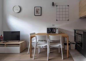 A modern kitchen with a microwave, oven, and a dining table with chairs. - Hotiday Milano Frattini (Milan)