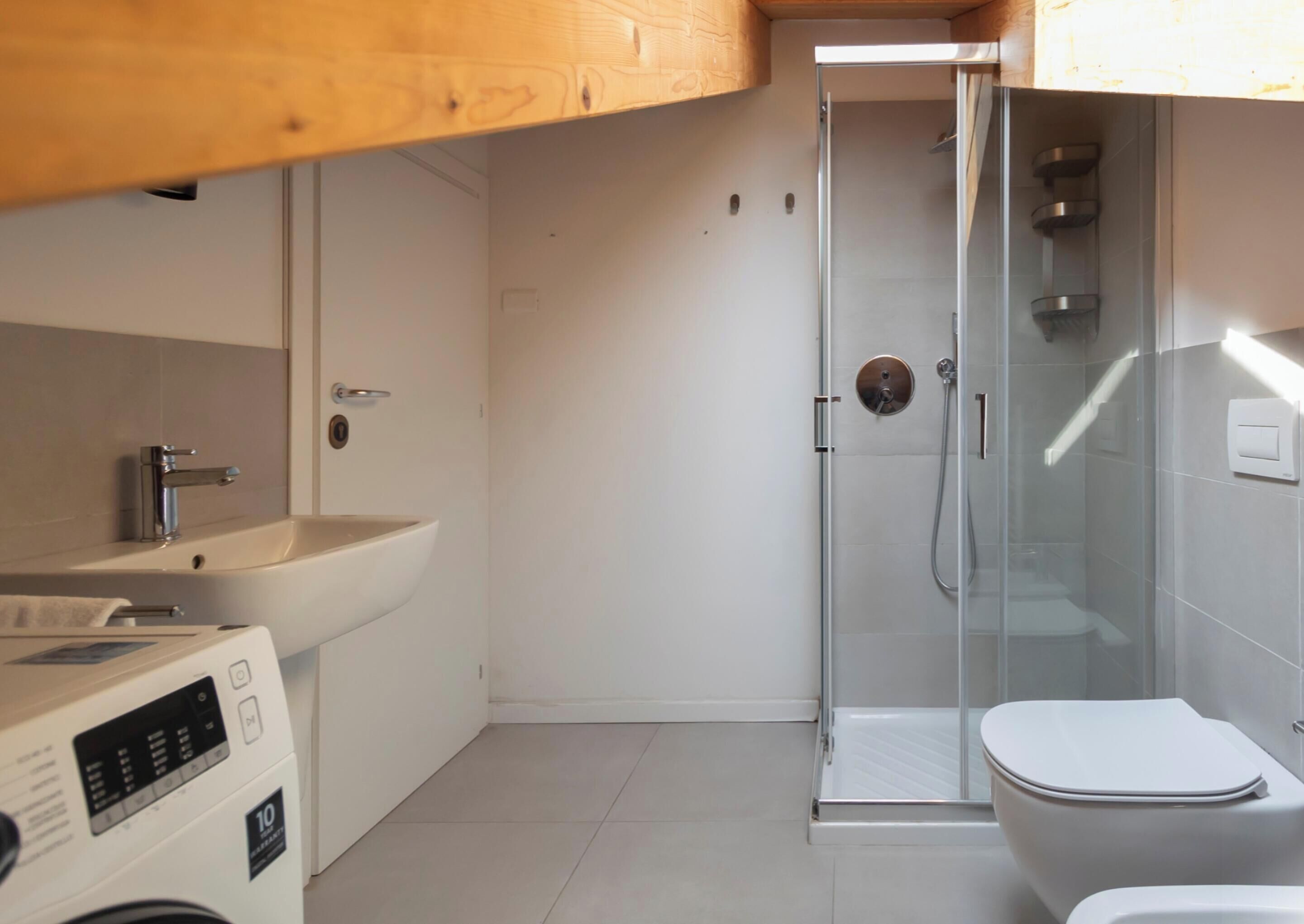 A modern bathroom with a glass shower enclosure, a white sink, and a toilet.