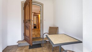 Ein Zimmer mit Holztür, einem kleinen Tisch und einem Stuhl.