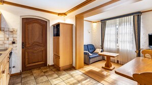 Ein Zimmer mit Holztür, Schrank, Sofa, Tisch und Fernseher.