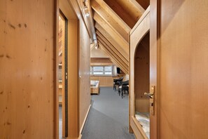 Un intérieur en bois avec un plafond en pente, un lit, un bureau et deux chaises.
