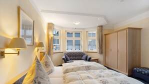 Ein Schlafzimmer mit Bett, Stuhl, Kleiderschrank und einem fenster mit Vorhängen.
