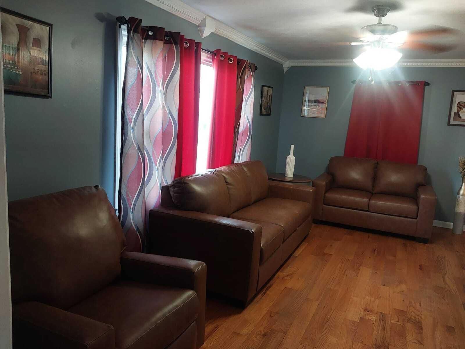 Un salon avec deux canapés en cuir marron, un plancher en bois et un ventilateur de plafond.