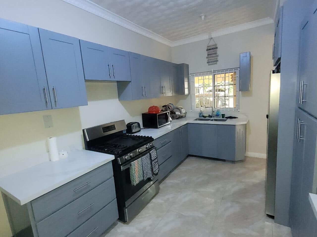 Una cocina moderna con armarios azules, una estufa negra y un refrigerador de acero inoxidable.