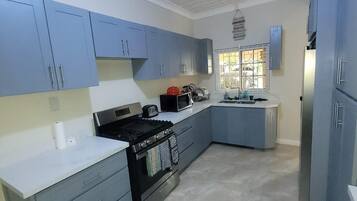 Una cocina moderna con armarios azules, una estufa negra y un refrigerador de acero inoxidable.