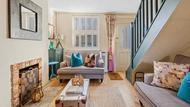 A cozy living room with a fireplace, a sofa, a coffee table, and a staircase. - Maple Cottage in Henley (Henley-On-Thames)