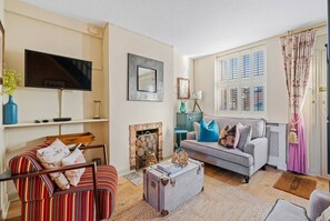 Una sala de estar con televisor, chimenea, sofá y mesa de centro.