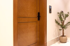A wooden door with a digital lock and a welcome sign.