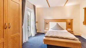Une chambre à coucher avec un lit en bois, une armoire et une fenêtre avec des rideaux.