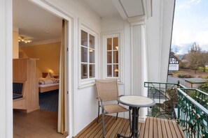 A room with a bed, a chair, and a table on a wooden deck. - Room 'Luxury Room' with Wi-Fi (Attendorn)