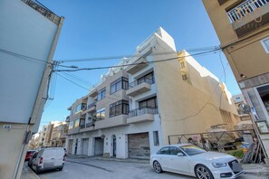 Un edifici residencial de diversos pisos amb balcons, un garatge i un cotxe estacionat.