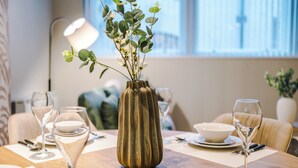 A dining table with a vase of green foliage, a wine glass, and a bowl. - Stylish 2 Bed 2 Bath Apartment – Liverpool Centre (Liverpool)