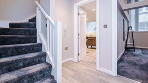 A staircase leading to a room with a wooden floor and a view of a living area with a sofa and a window. - Stylish 2 Bed 2 Bath Apartment – Liverpool Centre (Liverpool)