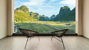 Een kamer met een groot raam en uitzicht op een bergachtig landschap.
