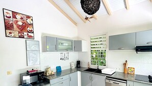 Una cocina moderna con armarios grises, encimera negra y ventana con vista a la vegetación.