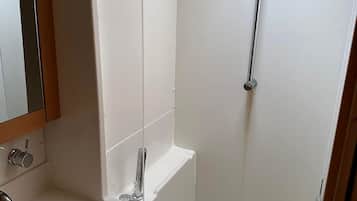 Un baño con ducha, lavabo y espejo.