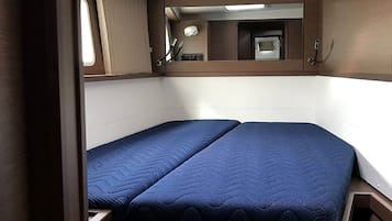 Un interior pequeño con una cama, un ventanal y un espejo.
