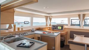 A compact galley with a stove, sink, and a small dining area with a table and bench.