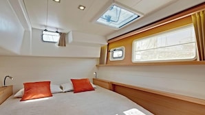 A bedroom with a bed, two windows, a skylight, and a small window.