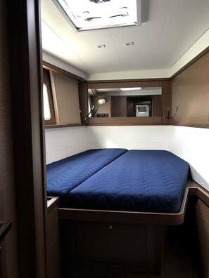 A compact interior with a bed, a small window, and a mirror.