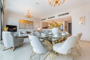 Un espace de salle à manger moderne avec une table en verre, des chaises blanches et un lustre.