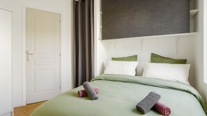 A bedroom with a bed, pillows, a door, and curtains.