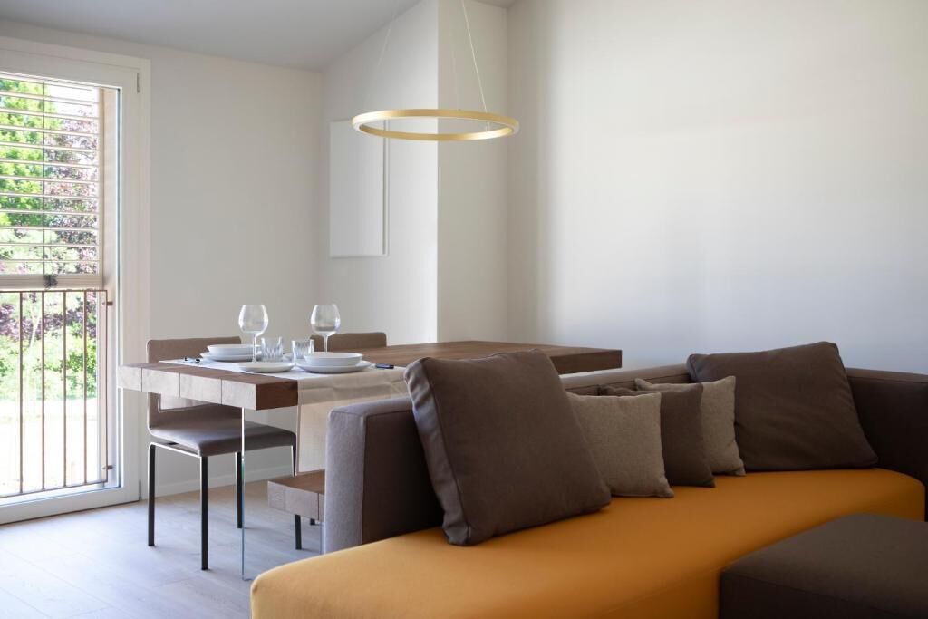 Un espace repas moderne avec une table dressée pour deux personnes, un canapé et un luminaire suspendu.