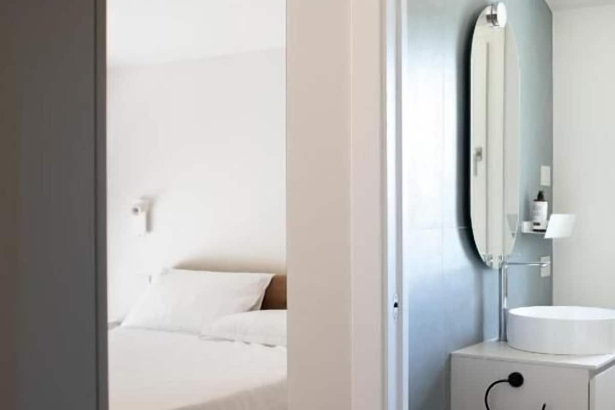 A modern bathroom with a round sink, a mirror, and a white cabinet.