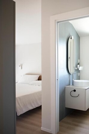Ein modernes Badezimmer mit einem runden Waschbecken, einem Spiegel und einem weißen Korpus.