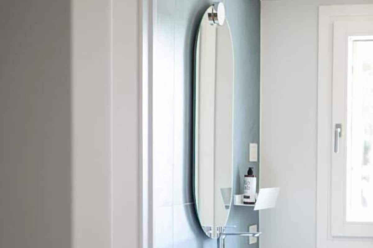 A bathroom with a white vanity, a round mirror, and a light fixture.