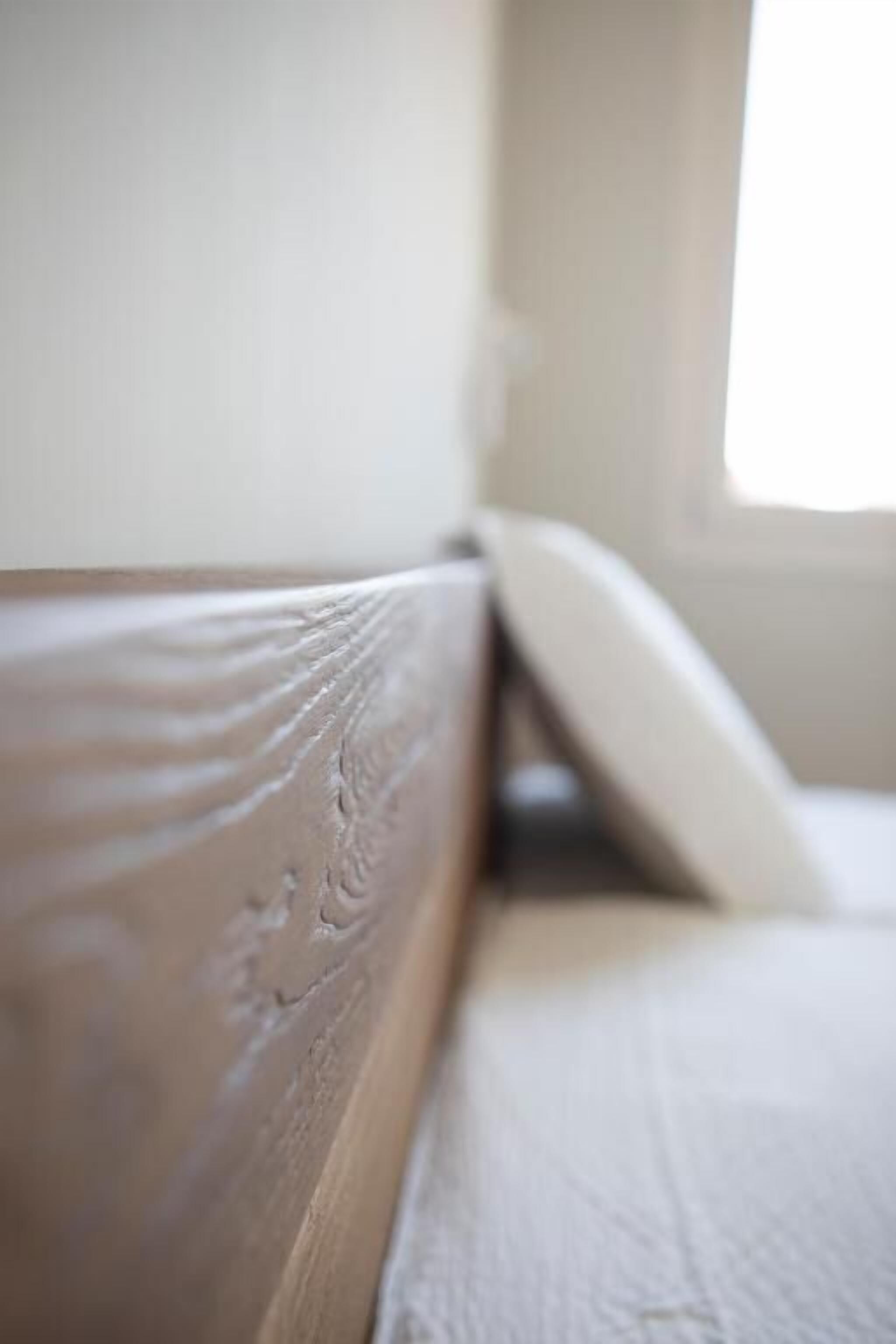 A close-up of a wooden headboard with a textured finish.