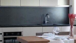 Et moderne køkken med indbyggede apparater, et spiseområde med et træbord og en sofa.