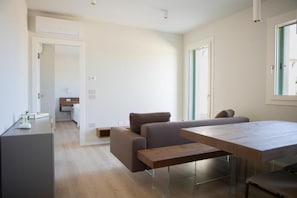 Un espace de vie moderne avec un canapé, une table en bois et un coin cuisine à l’arrière-plan.