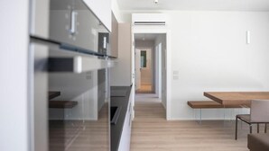Et moderne køkken med indbygget ovn og spiseplads med et træbord og stole.