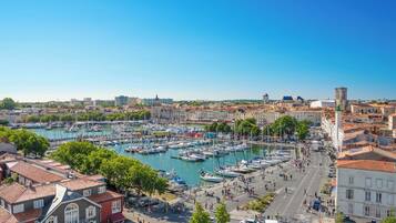 Un port de plaisance avec des bateaux, un paysage urbain avec des bâtiments historiques et un ciel dégagé.