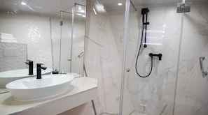 A modern bathroom with a glass-enclosed shower, a white sink with black fixtures, and marble walls. - Sun-Kissed Sailing Adventure in Split, Croatia (Split)