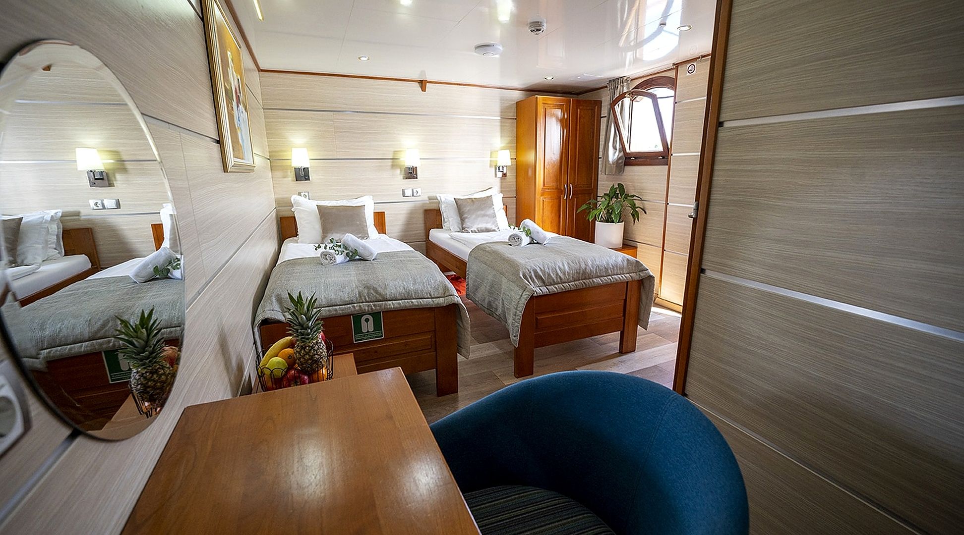 A compact, well-lit cabin with two beds, a dining table, and a seating area.