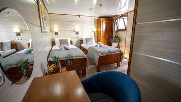 A compact, well-lit cabin with two beds, a dining table, and a seating area.