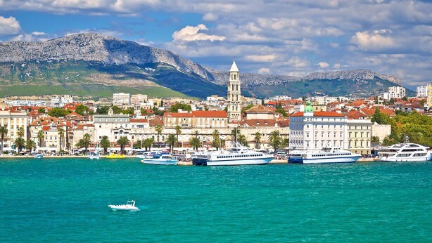 A coastal cityscape with a prominent tower, boats, and a mountainous backdrop. - Sun-Kissed Sailing Adventure in Split, Croatia (Split)