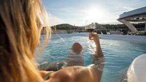 A person in a swimming pool holding a glass of wine, with a clear sky and a building in the background. - Sun-Kissed Sailing Adventure in Split, Croatia (Split)