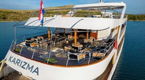 A large yacht named KARIZMA with a spacious deck, multiple seating areas, and a flag.