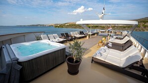 A yacht deck with a hot tub, lounge chairs, and a dining area overlooking the sea. - Sun-Kissed Sailing Adventure in Split, Croatia (Split)