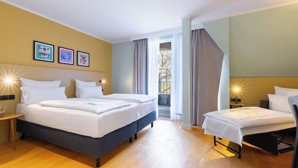 Una habitación de hotel con dos camas, una mesita y una ventana con cortinas.