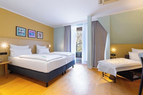 Een hotelkamer met twee bedden, een kleine tafel en een raam met gordijnen.