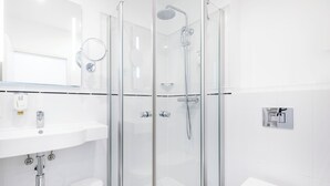 Un baño moderno con ducha acristalada, lavabo blanco y retrete.