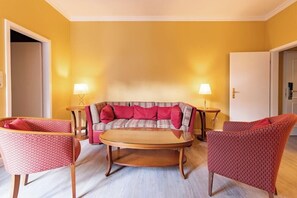 A living room with a sofa, two armchairs, a coffee table, and two lamps. - Garner Hotel Berlin Messe by IHG (Berlin)