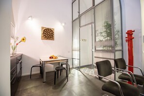 Ein modernes Zimmer mit Glaswand, Obst auf einem Tisch, Blumen in einer Vase und einer roten Skulptur.