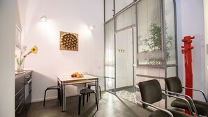 A modern room with a glass wall, a table with fruit, a vase with flowers, and a red sculpture. - GuestHost - A practical and welcoming 50 square meters open-plan loft, perfect for two people, located on the ground floor of an elegant building with a courtyard.The property is located in the Prati district, one of Rome's most charming areas: our guest (Rome)