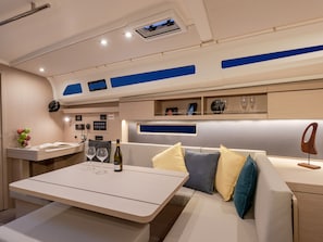 A modern interior with a seating area, a table with a bottle and glasses, and a control panel.