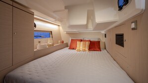 A bedroom with a bed, pillows, a mirror, and a window with a view. - Sun-Kissed Sailing Adventure in Split-Dalmatia, Croatia (Marina)